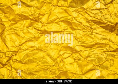 Golden yellow background with heavy wrinkles. Golden yellow recycled kraft paper texture as background. Stock Photo