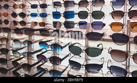 Sunglasses rows on display in the market. Sunglasses. Glasses of different shapes and colors. Sales merchandise concept background Stock Photo