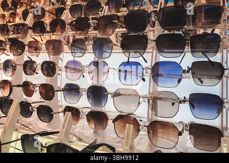 Sunglasses rows on display in the market. Sunglasses. Glasses of different shapes and colors. Sales merchandise concept background Stock Photo