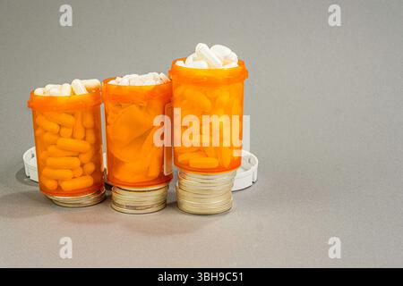 Three overful prescription bottles stack on a ladder of Silver Dollars. Expense is the concept. Stock Photo