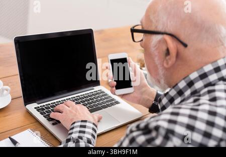 Senior man using laptop and smartphone mockup Stock Photo