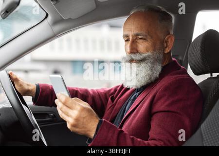 Elderly man driving new car, using mobile phone Stock Photo