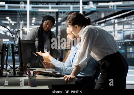 Data center engineering team doing brainstorming, monitoring system performance using computer, identifying bottlenecks. Server farm coworkers troubleshooting errors, implementing optimizations Stock Photo