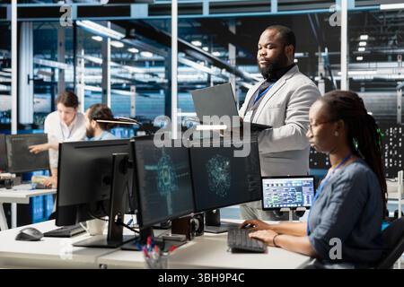 Data center IT experts using artificial intelligence neural networks technology. African american server farm facility software developers using AI programming language on computer to update hardware Stock Photo