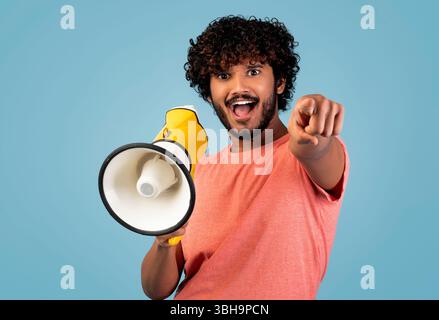 Handsome eastern guy shouting through loudspeaker and gesturing Stock Photo