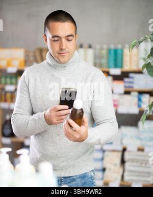 Male buyer scans code on cough syrup to check expiration date Stock Photo