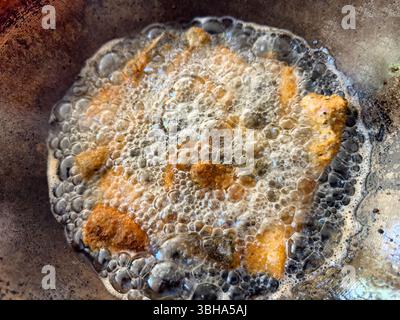 Close up of bread coated salmon fish being deep fried in pan with hot oil searing Stock Photo
