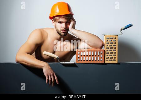 Crazy builder with bricks, funny sale on construction site. Funny man hold brick. Builder posing with bricks blocks. Bricklayer concept. Funky Stock Photo