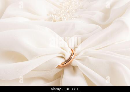 Chic soft fabric in a delicate creamy color inside two gold wedding rings. wedding composition. Front view. A copy of the space. layout for design Stock Photo