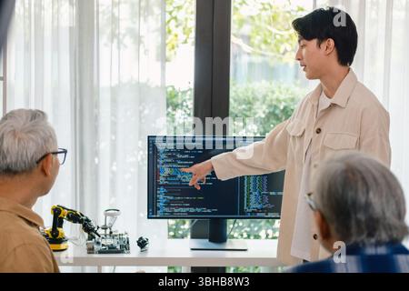 senior programmer bootcamlp,Asian young instructor guides senior learners through a programming on whiteboard, highlighting algorithm thinking and sim Stock Photo