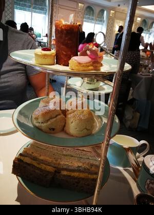 Elegant Afternoon Tea Featuring Sandwiches, Scones, and Assorted Desserts in a Luxury Setting. London, UK Stock Photo