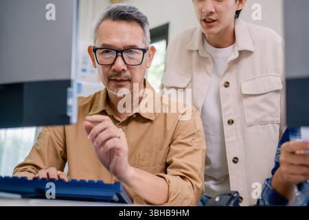 Asian senior bootcamp team asking and  learning programming with software training and whiteboard collaboration Stock Photo