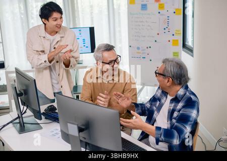 Senior developer team celebrates success in software collaboration and coding at a modern computer workstation Stock Photo