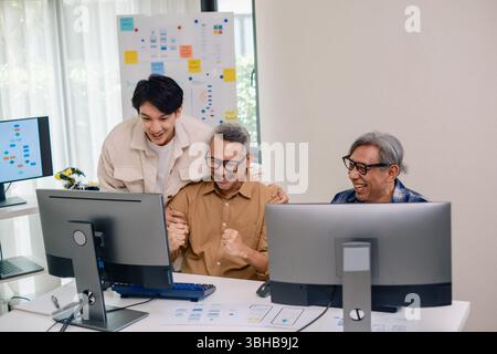 Senior developer team celebrates success in software collaboration and coding at a modern computer workstation Stock Photo