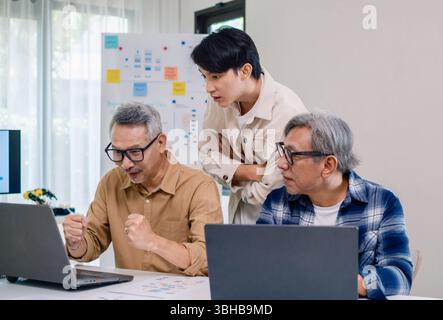 Senior developer team celebrates success in software collaboration and coding at a modern computer workstation Stock Photo