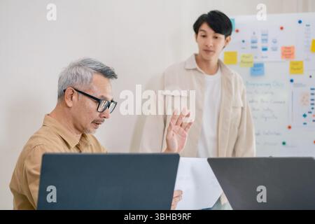 Asian senior bootcamp team asking and  learning programming with software training and whiteboard collaboration Stock Photo
