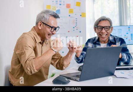 Senior developer team celebrates success in software collaboration and coding at a modern computer workstation Stock Photo