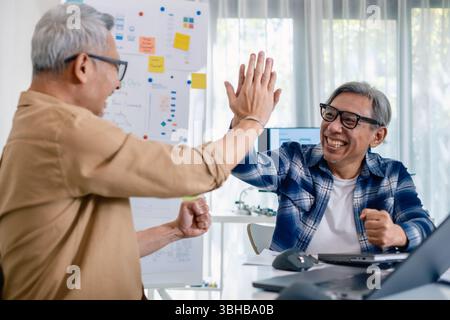 Senior developer team celebrates success in software collaboration and coding at a modern computer workstation Stock Photo