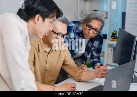 Team of developers collaborating in brainstorming and coding project at office workspace Stock Photo
