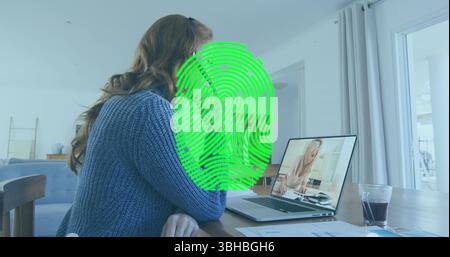 Image of biometric fingerprint scanner over caucasian woman having a imagecall on laptop at home. Cyber security and business technology concept Stock Photo