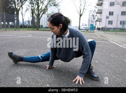 Young woman stretching her legs before street dancing practice. Stock Photo