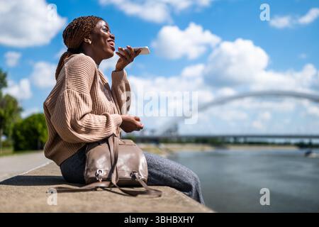 Young cheerful black woman is talking on the phone. She is laughing. Stock Photo