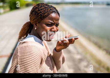 Young black woman is talking on the phone. She is anxious and worried. Stock Photo