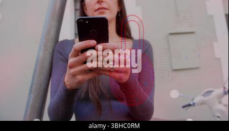 Image of security padlock icon over caucasian woman using smartphone outdoors. Cyber security and business technology concept Stock Photo