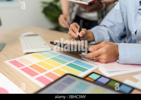 Creative Process in UX and UI Design. Designer working on a tablet with color swatches. Stock Photo