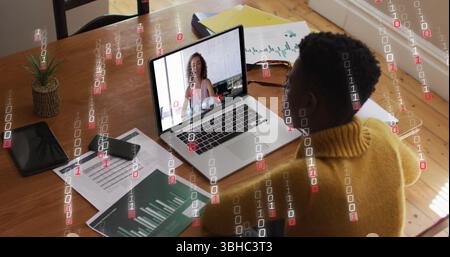 Image of binary coding over african american woman having a image call on laptop at home. Global networking and business technology concept Stock Photo