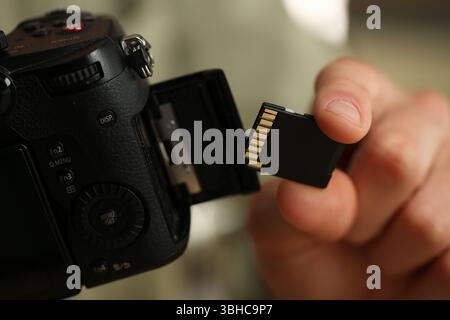 Man inserting SD memory card into photo camera, closeup Stock Photo