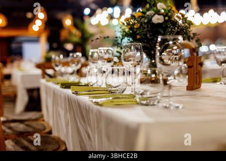 Romantically set dinner table with wine glasses and floral centerpiece, perfect for a wedding, elegant party, or outdoor evening celebration. Warm lig Stock Photo