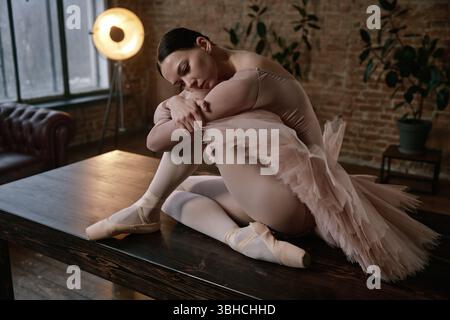 An elegant ballerina is posing gracefully on a table in a beautiful artistic setting Stock Photo