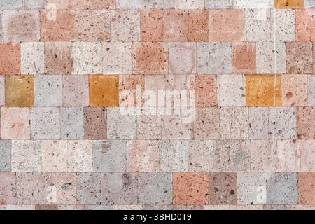 The textured wall is lined with volcanic tuff tiles of various shades. Stock Photo