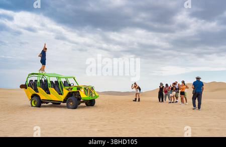 Ica, Peru - March 12, 2025: A group of tourists taking photos an enjoying the dune buggy adventure in the Ica desert, Huacachina Stock Photo