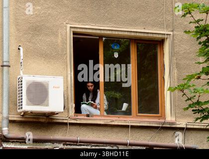 Young woman reading at apartment window Stock Photo