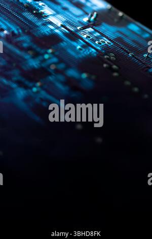 Close-up of an illuminated blue electronic circuit board with electrical components and connections, isolated on black, selective focus. Copy space Stock Photo