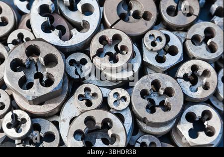 Bolt threading dies. Many dies of different sizes, top view. Hand tool ...