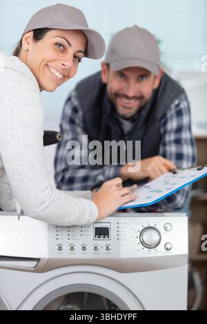 female and male plumber repairing washing machine Stock Photo