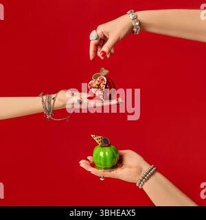 Pastry chefs holding mini apple-shaped cakes on red background Stock Photo