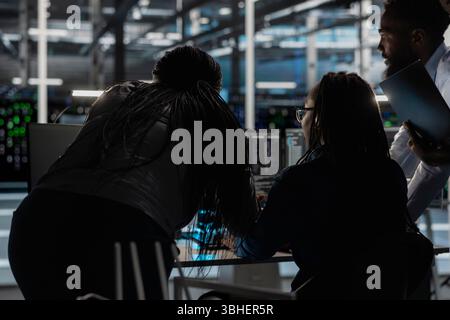 Server farm engineering team implementing and managing data backup solutions. Teamworking data center colleagues identifying and resolving technical errors, ensuring efficient recovery Stock Photo