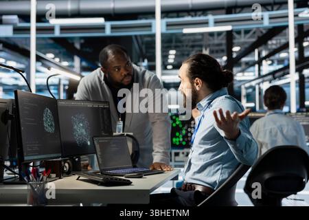 Data center manager berating employee during intense discussion, reproaching performance issues. Technician in server hub receiving verbal reprimand from upset management team leader Stock Photo