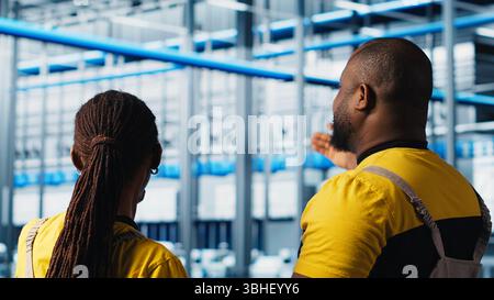 Industry 4.0 industrial plant engineering team controlling automated machinery using tablet, ensuring workflow continuity. Teamworking smart factory colleagues manage robotic arms, camera A Stock Photo