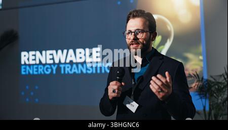 Microphone, presentation and businessman on a stage at seminar for renewable energy transition. Public speaker, conference and male environmental Stock Photo