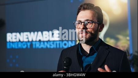 Microphone, presentation and businessman on a stage at conference for renewable energy transition. Public speaker, seminar and male environmental Stock Photo
