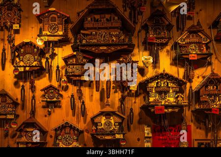 Traditional German cuckoo clocks on display in a shop in the Black Forest region, featuring intricate wooden carvings, detailed figurines. Stock Photo