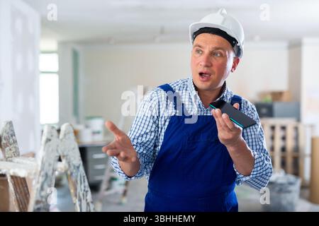 Foreman using smartphone, recording voice message Stock Photo
