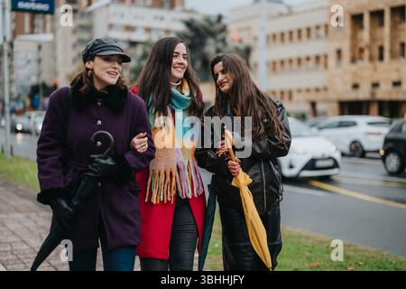Three women enjoying a stroll through city streets on a cloudy day Stock Photo