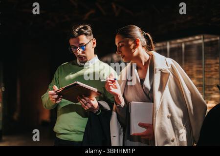 Two professionals collaborating and discussing notes inside a modern museum environment Stock Photo