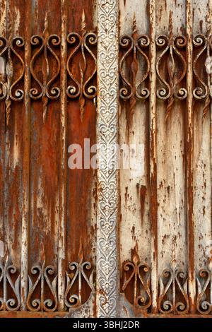 This scene showcases a weathered metal door featuring ornate decorative elements, displaying various shades of rust and peeling paint Stock Photo